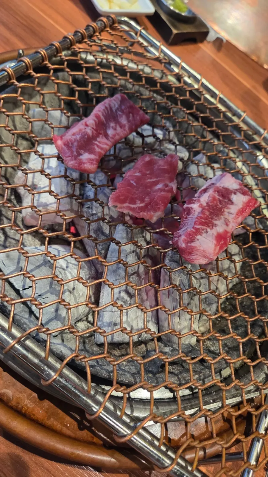 Fresh beef short ribs grilling on the charcoal grill plate