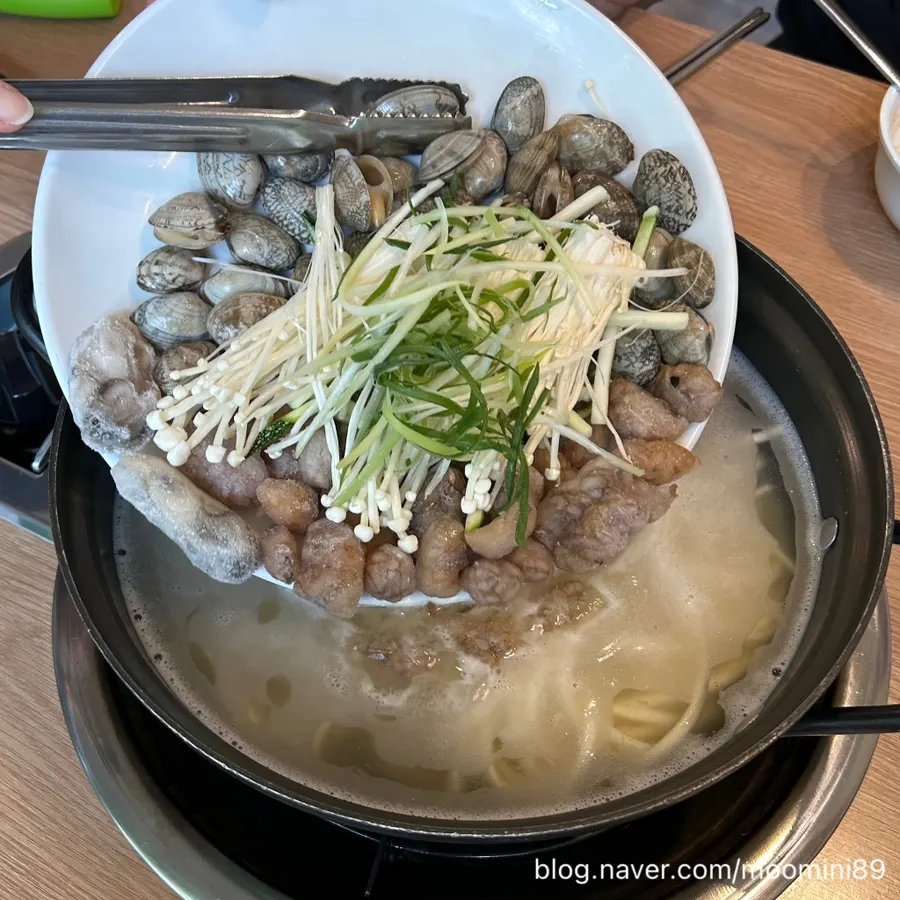 끓는 칼국수 냄비에 해물 넣는 모습