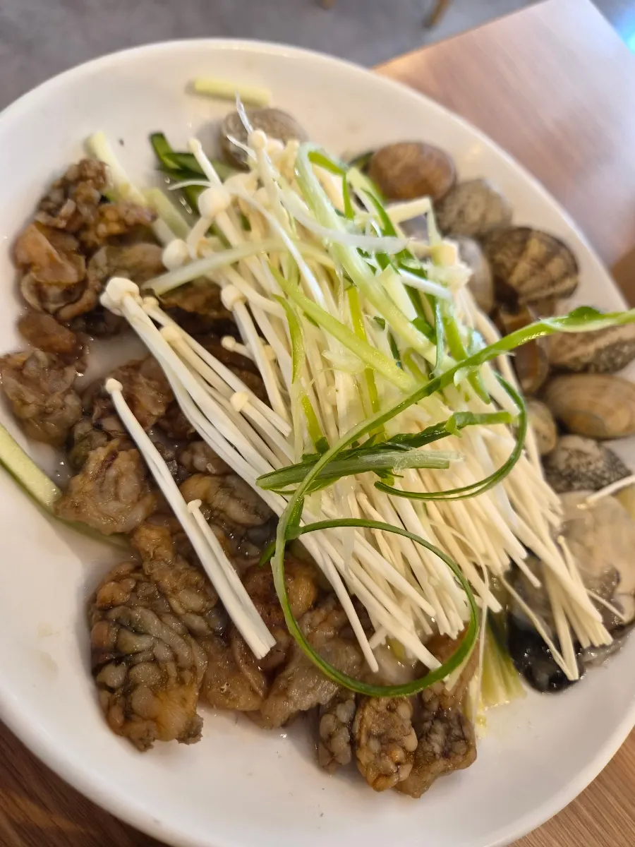 Table setting with a pot of pufferfish seafood kalguksu, single serving