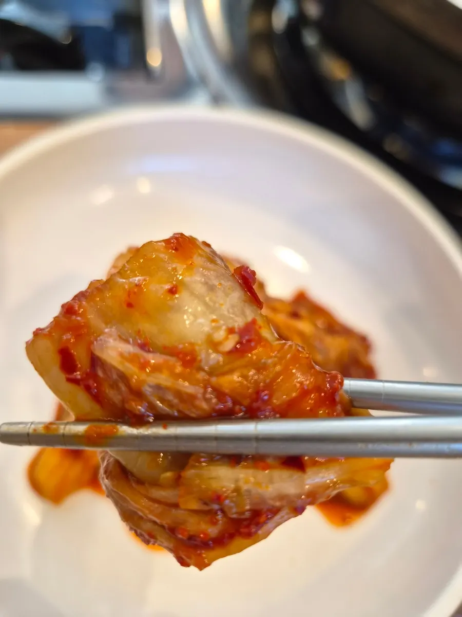 A bite of kalguksu topped with kimchi