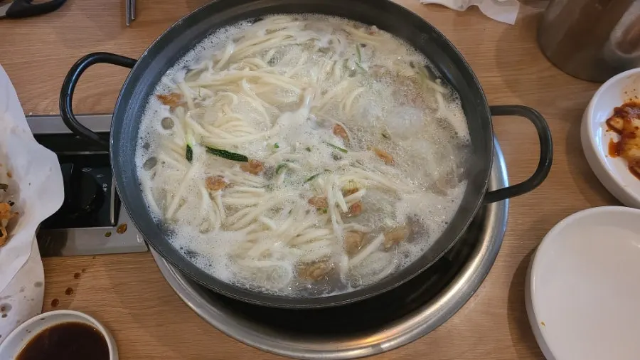 Spooning up broth from the seafood kalguksu