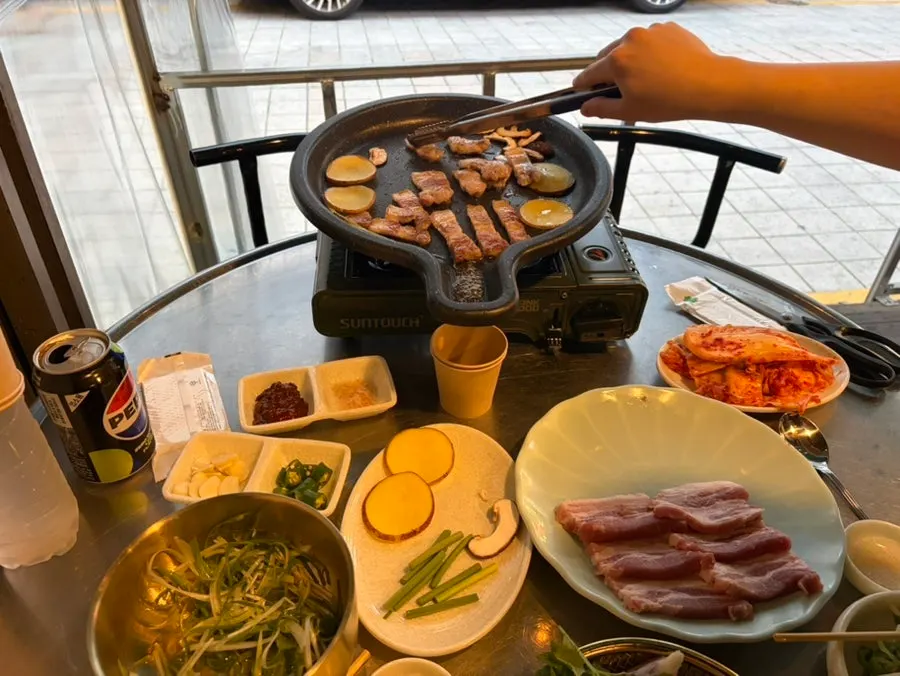불판 위에서 야채와 함께 구워지는 삼겹살