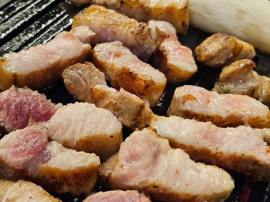 Aged pork belly grilling over charcoal