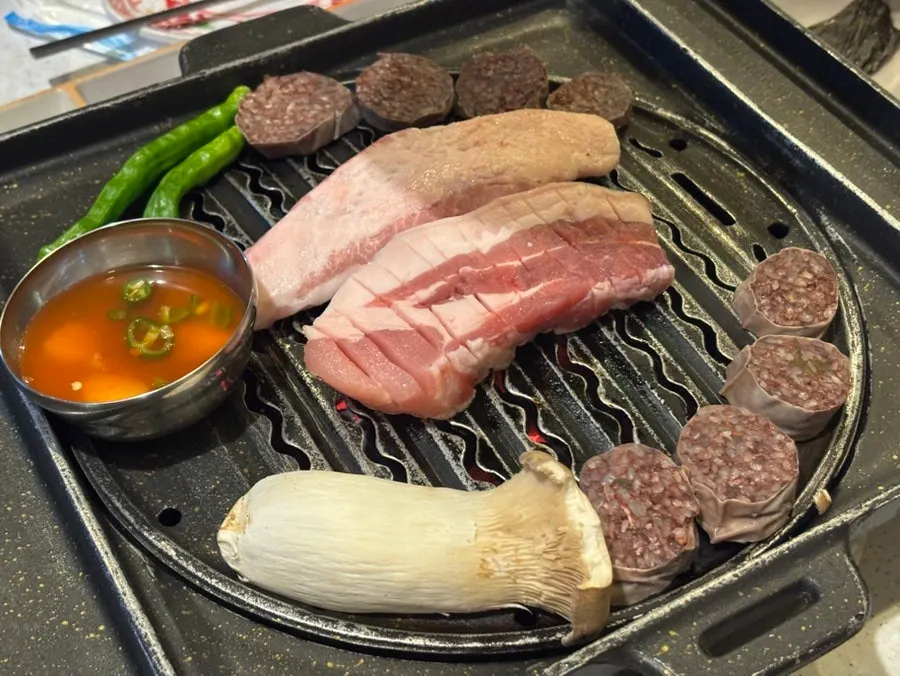 Black pork belly on the grill with sundae arranged around it