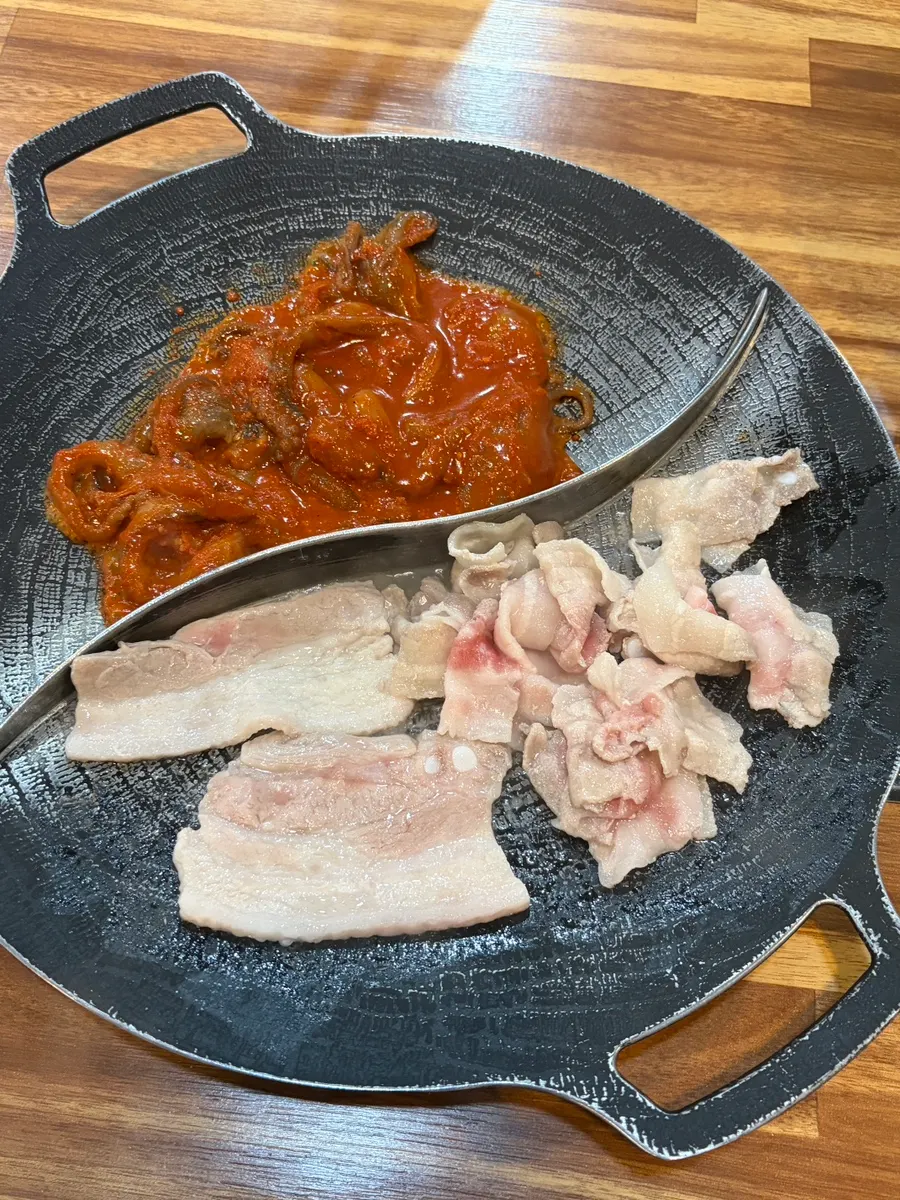 Jjukkumi on one side and pork belly on the other of the grill pan