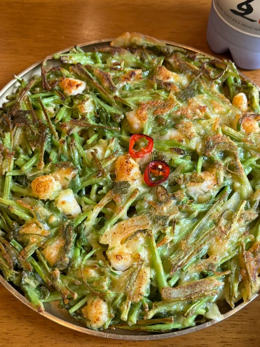 Substantial tongs and scissors set beside the shrimp minari pancake