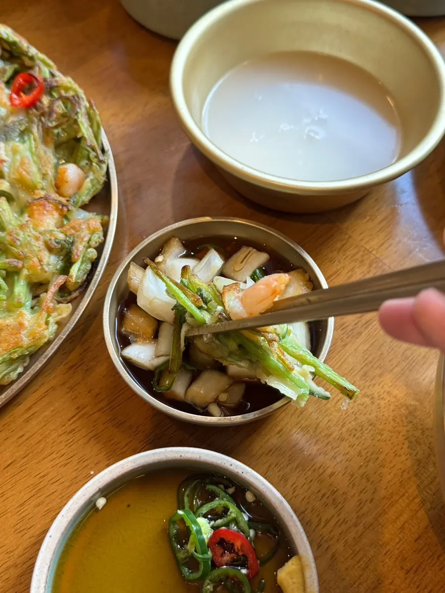 A glass of Seonho makgeolli with the shrimp minari pancake