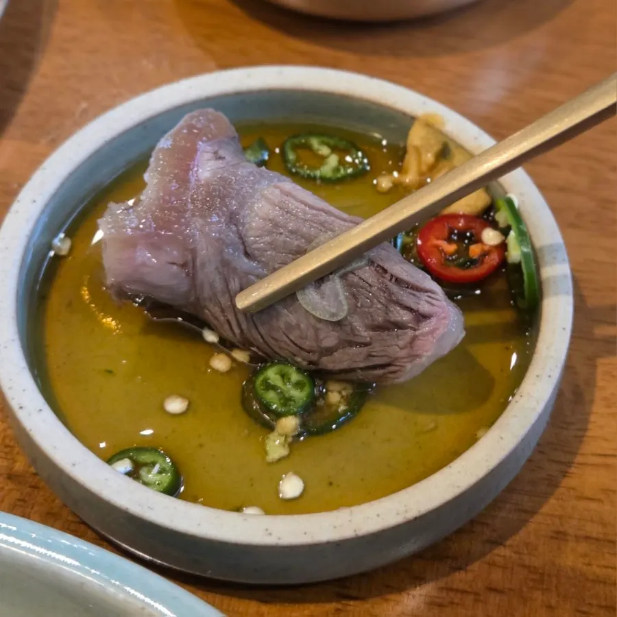 A piece of gomtang meat dipped in soy sauce