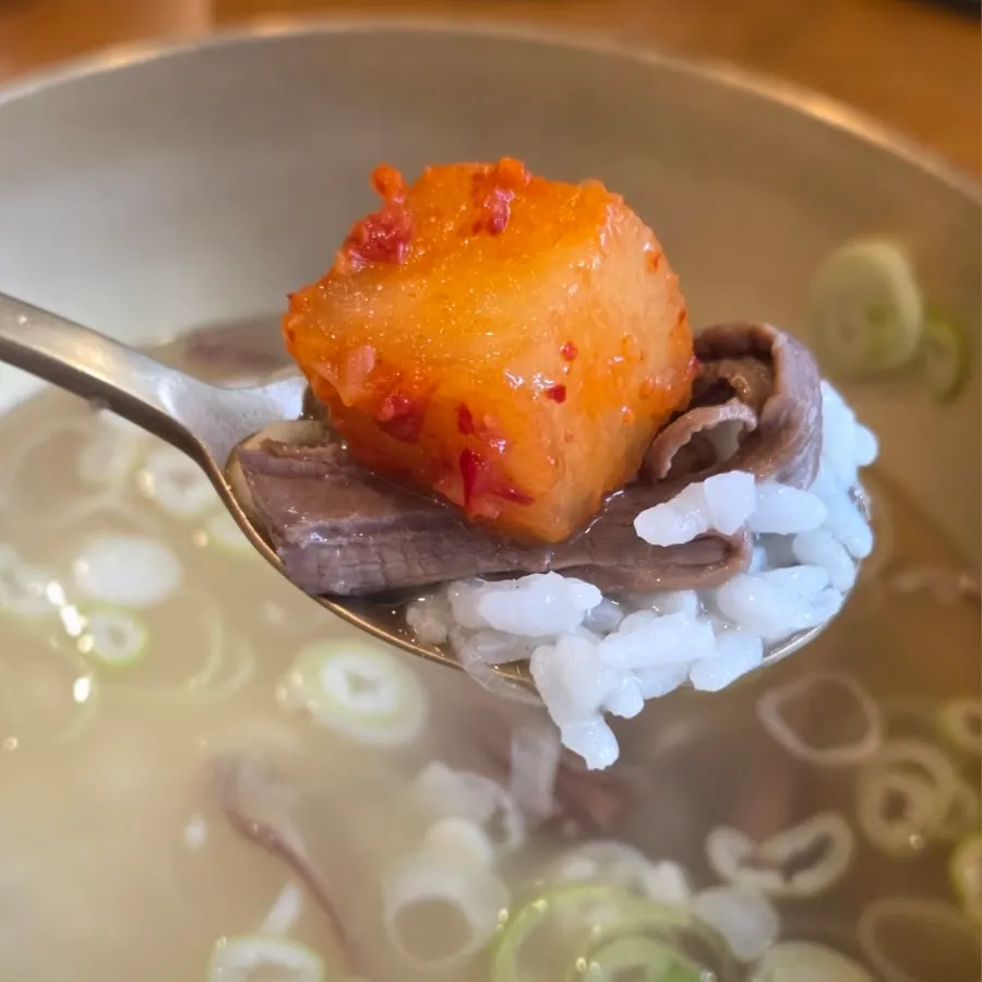 A spoonful of gomtang rice topped with kkakdugi