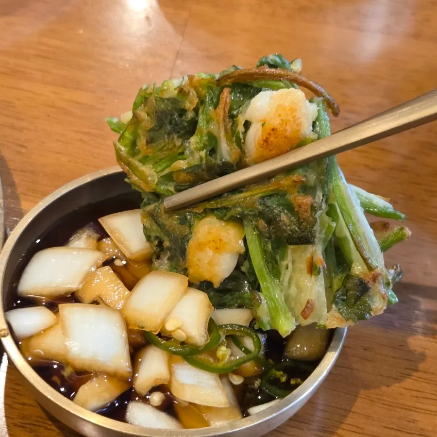 Shrimp minari jeon eaten with onion and seasoned soy sauce