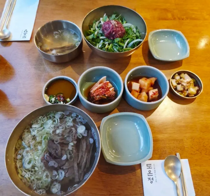 Yukhoe bibimbap, gomtang, and minari shrimp pancake table setting