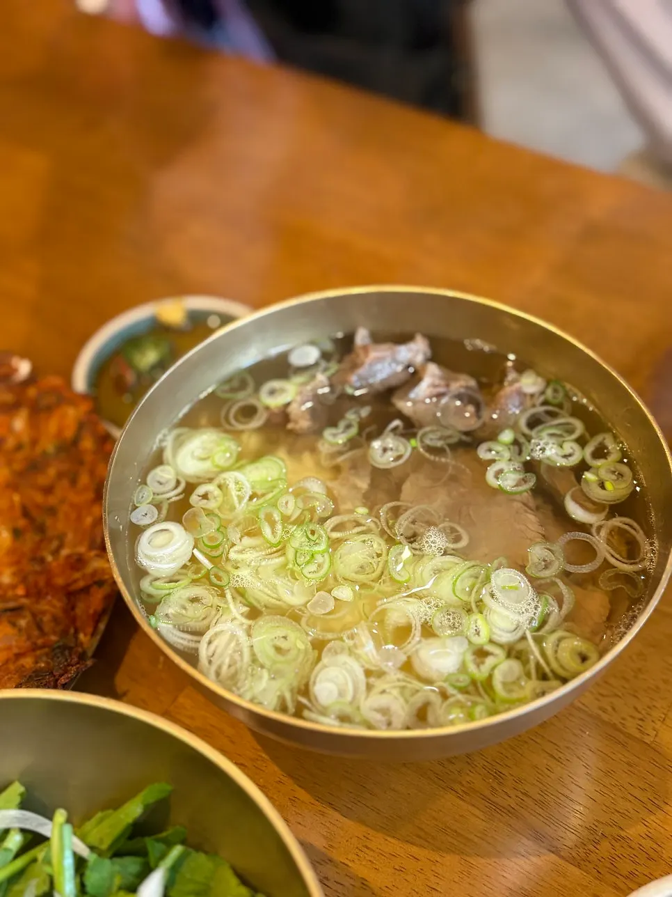 A bowl of sujigomtang topped with plenty of green onion