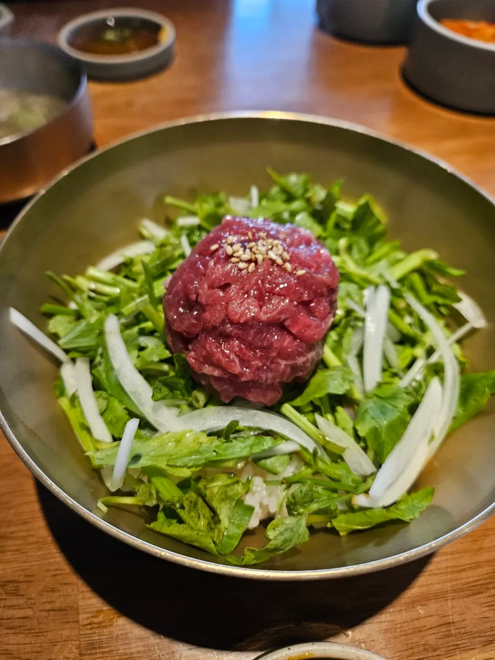 Hanwoo yukhoe bibimbap topped with raw beef and minari