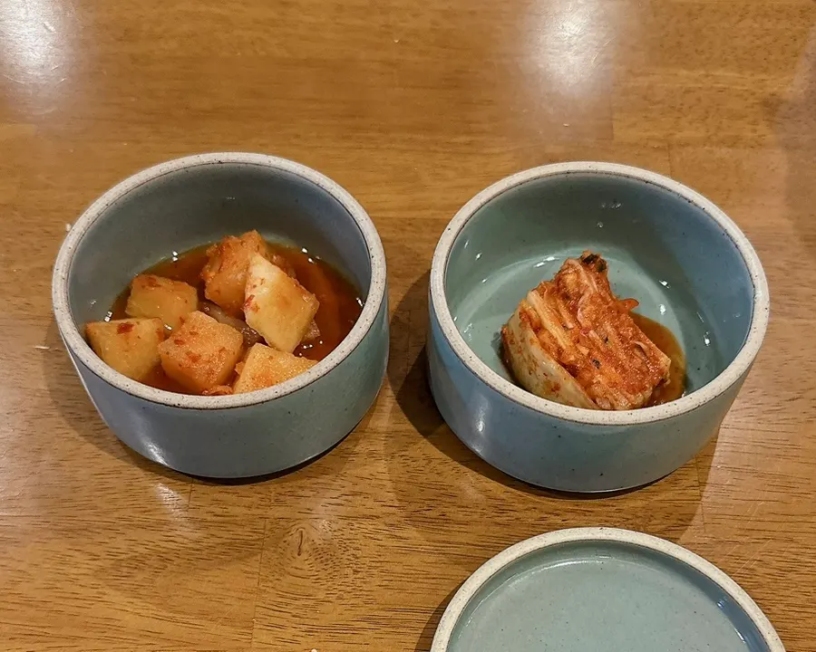 Napa cabbage kimchi and diced radish kimchi in ceramic bowls