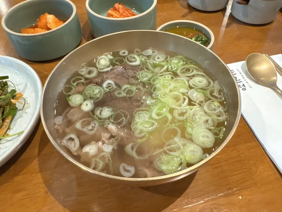 Clear hanwoo gomtang with tendon in a gold-toned bowl