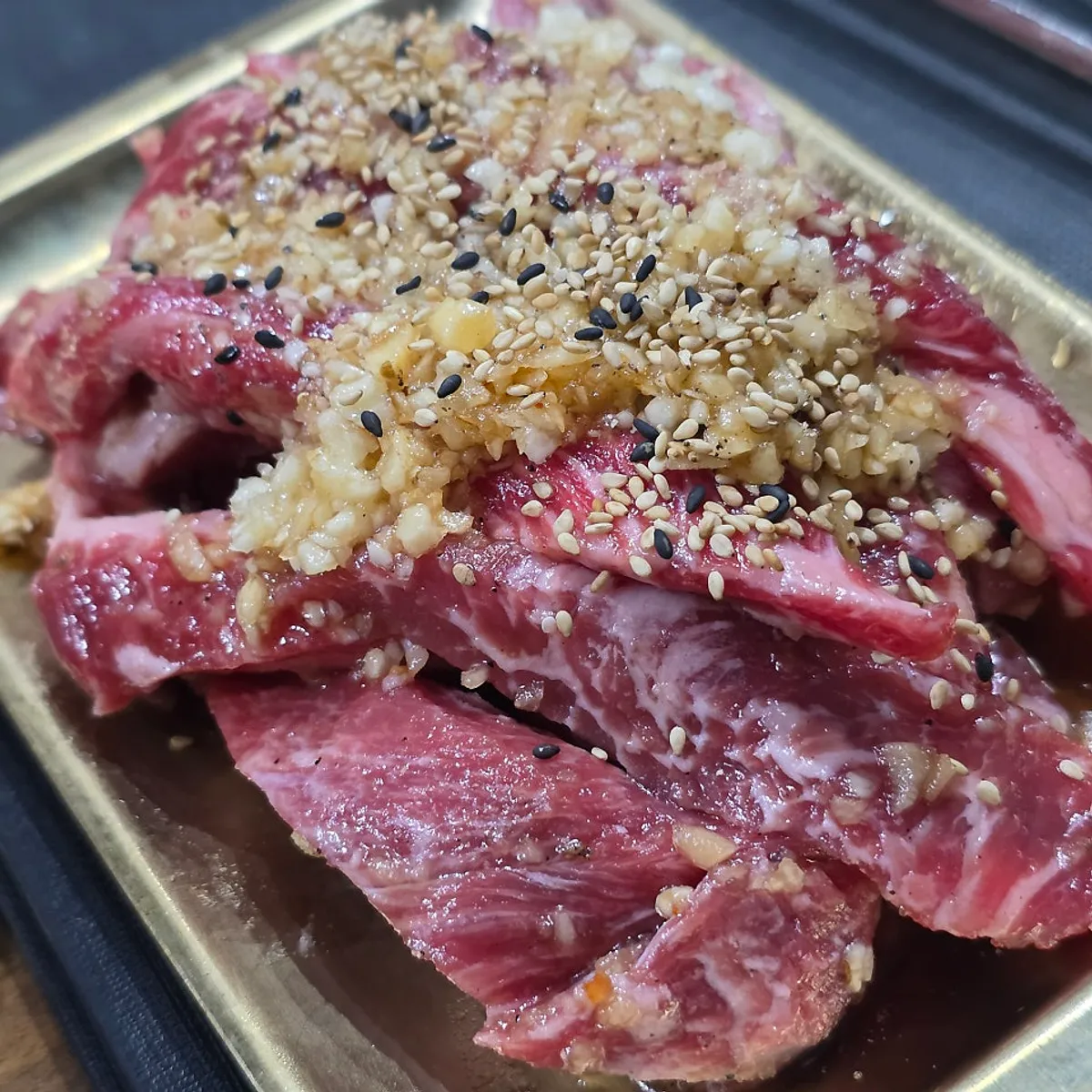Raw galbisal topped with minced garlic and sesame seeds
