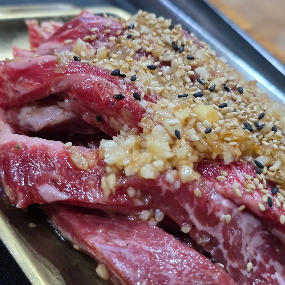 Short ribs grilling over charcoal alongside the banchan