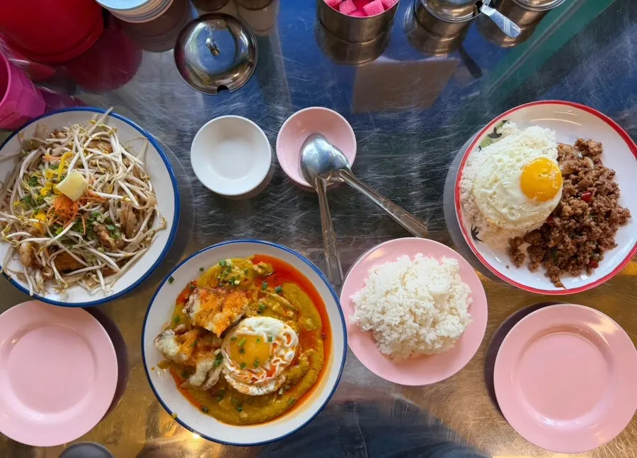 Table spread of pad thai, poo pad pong curry, and pad kra pao moo sap