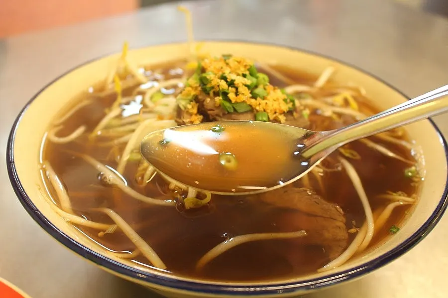A bowl of Thai-style rice noodle soup with rich broth
