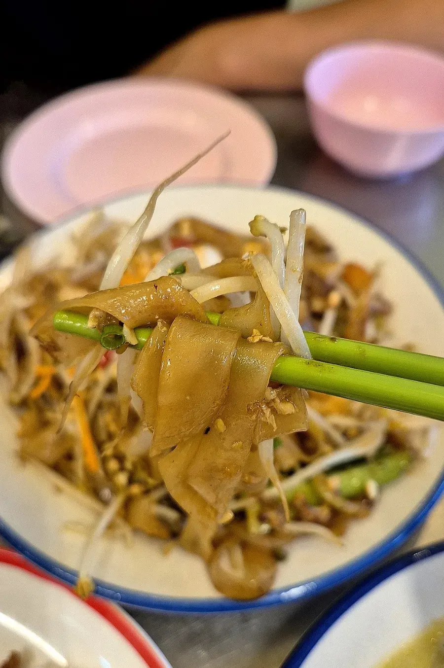 Wide pad see ew noodles lifted with chopsticks