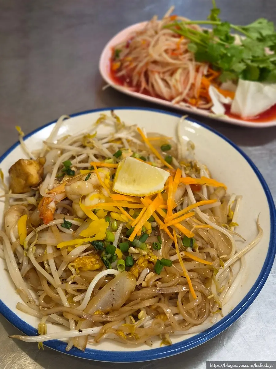 A plate of shrimp pad thai with a noodle refill