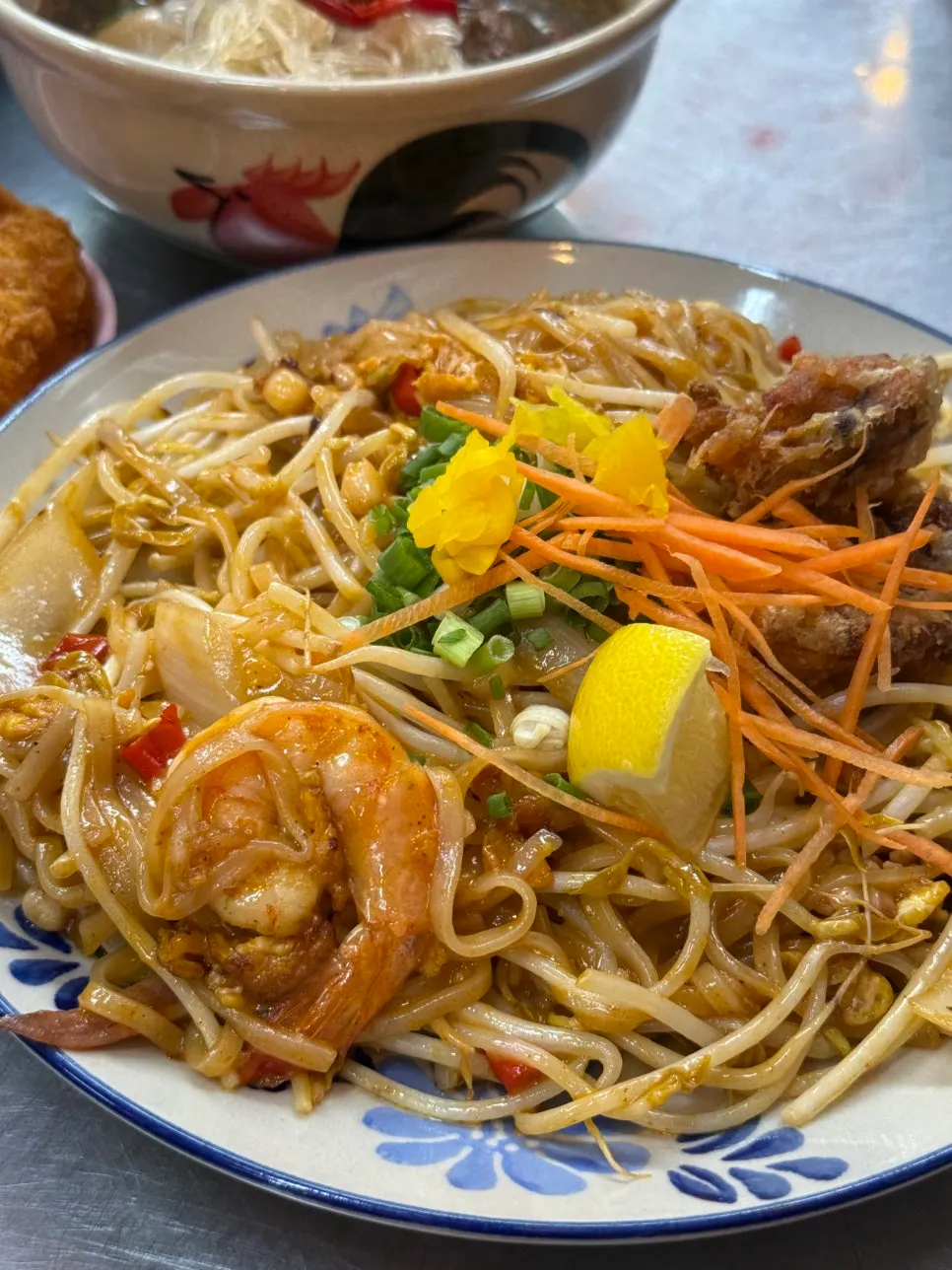 A plate of pad thai topped with seafood