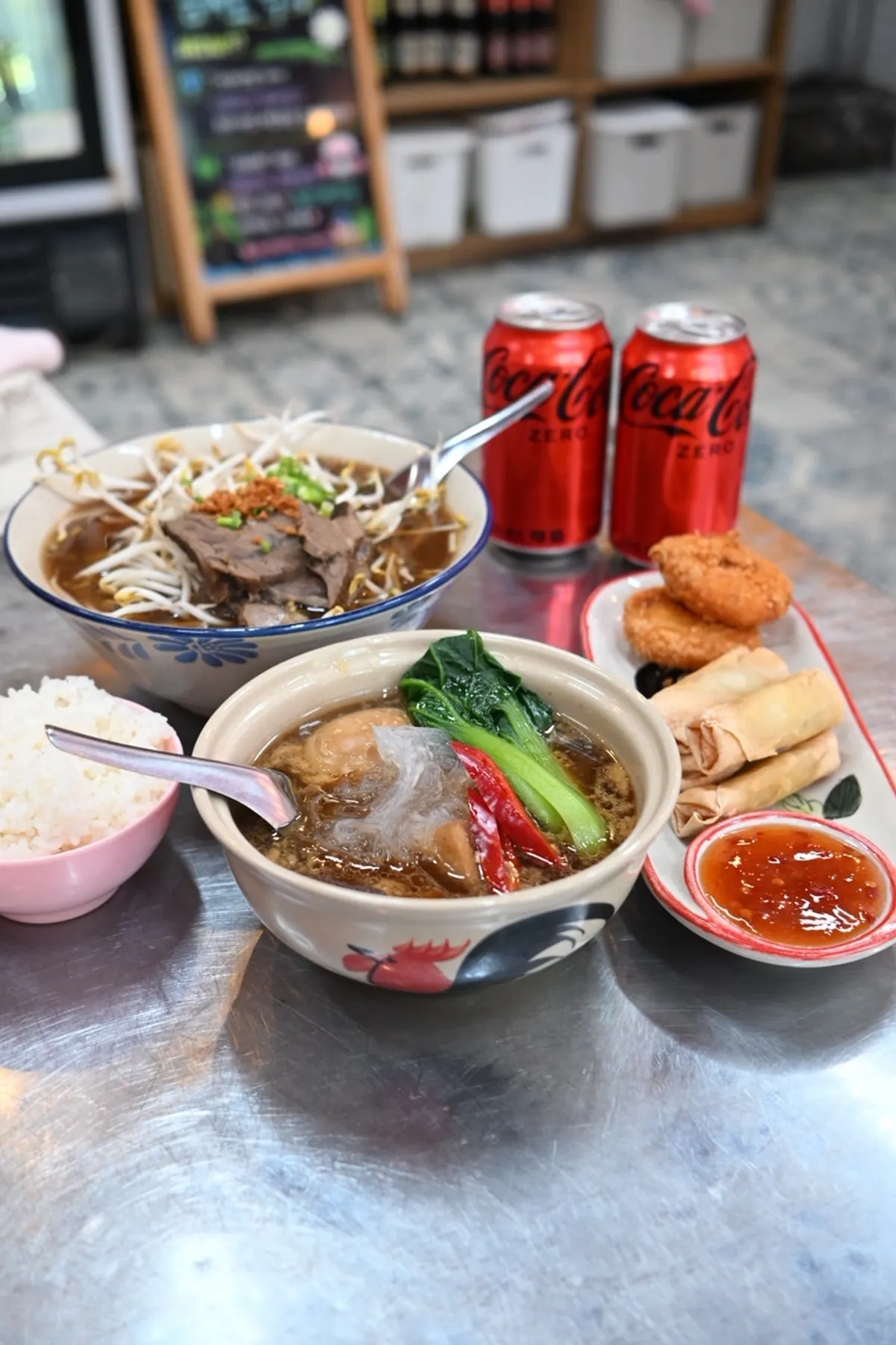 Full table spread of ordered dishes including beef pho and kai moo palo