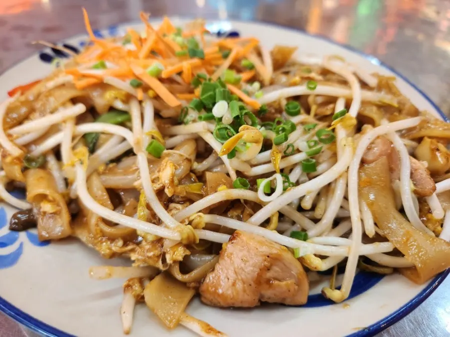 Seafood pad thai topped with bean sprouts and peanut powder