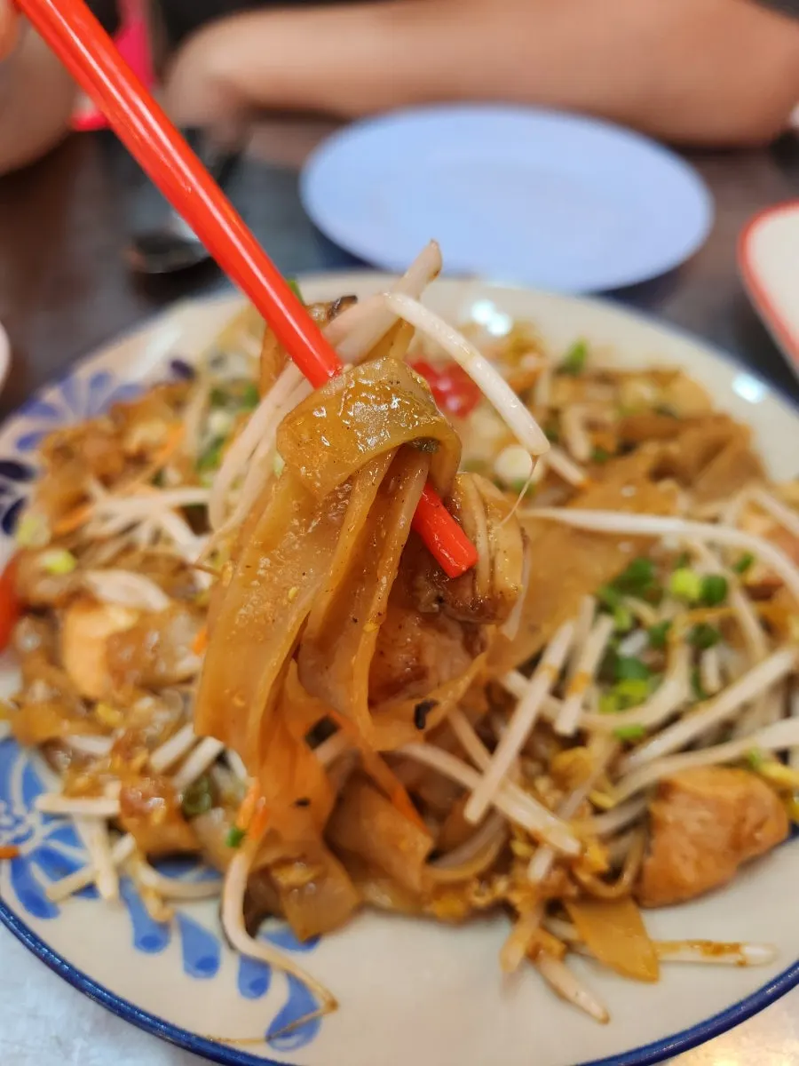 Lifting up a forkful of pad thai noodles