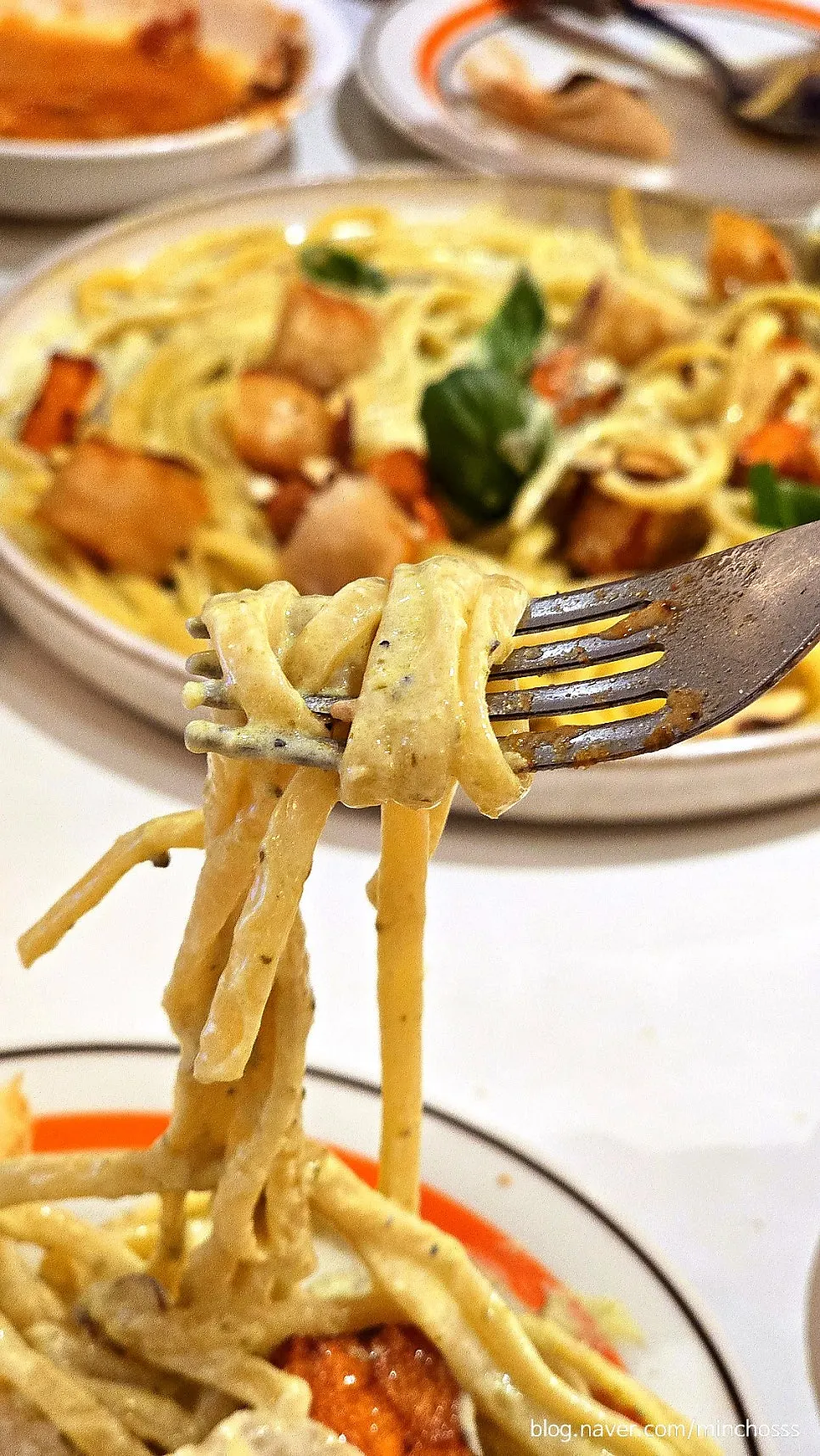 A bite of pasta with a scallop lifted up