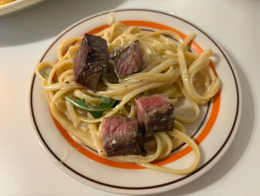 A bite of cream pasta with arugula