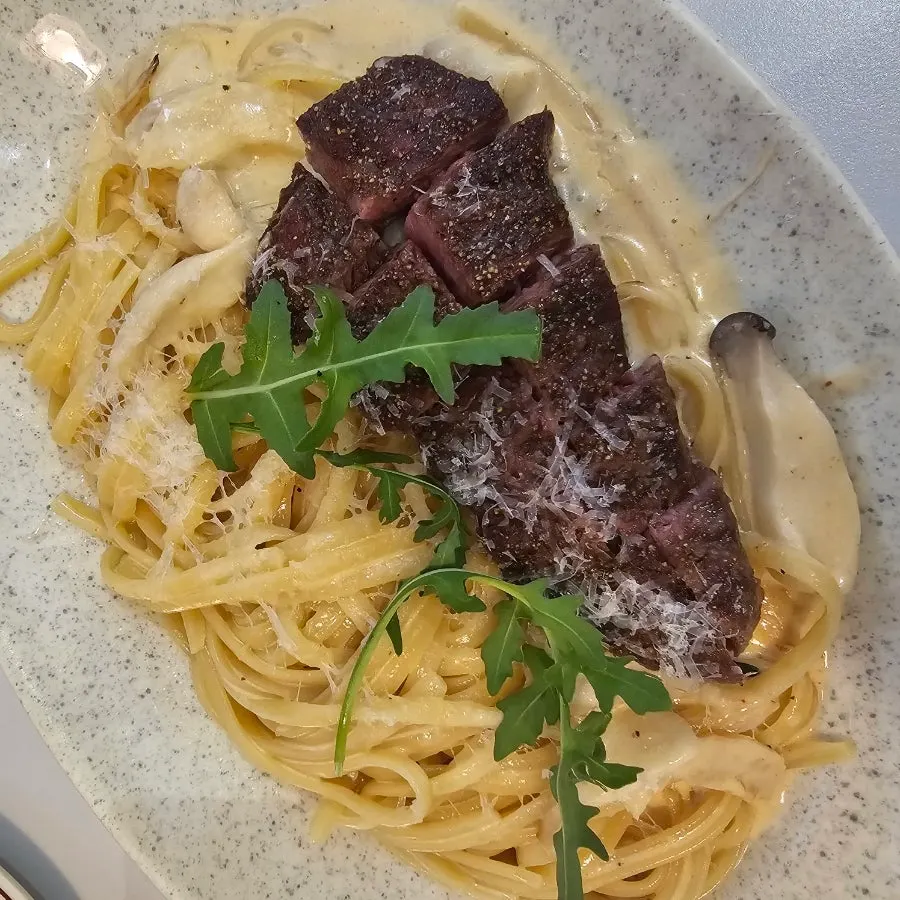 Beef flap meat on top of the cream pasta