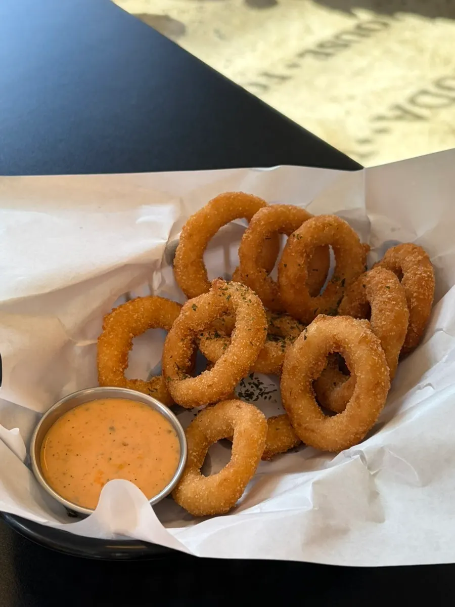 A generous serving of onion rings with sauce