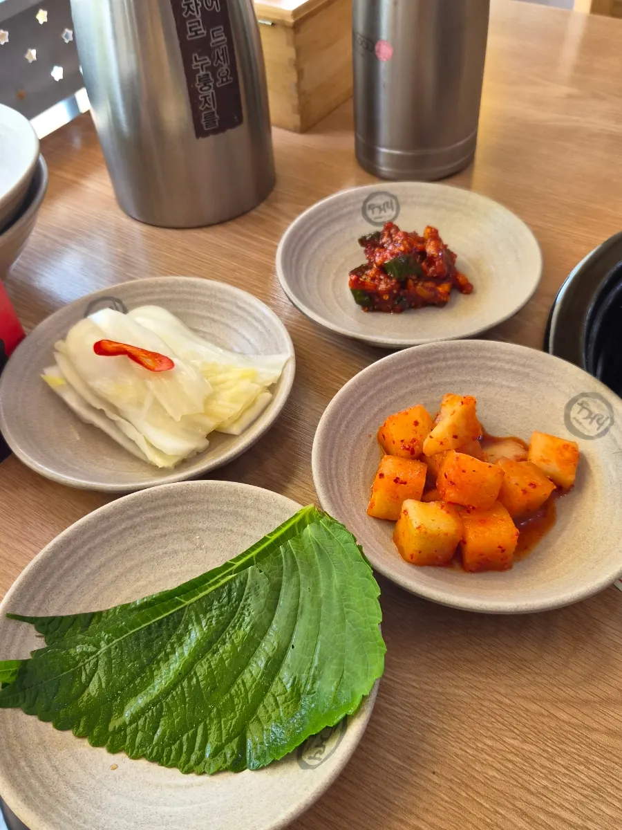 Table setting with kkakdugi, perilla leaves, white kimchi, and salted squid side dishes
