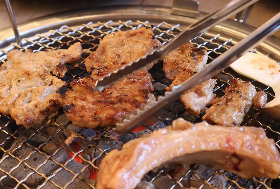 Seasoned pork galbi grilling over charcoal