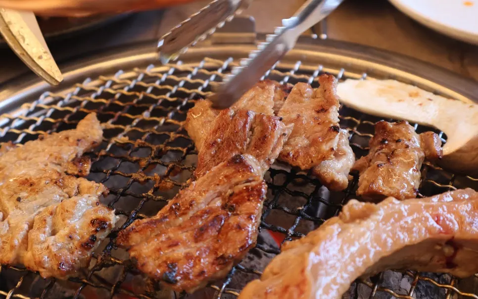 Seasoned galbi cooking over the charcoal grill