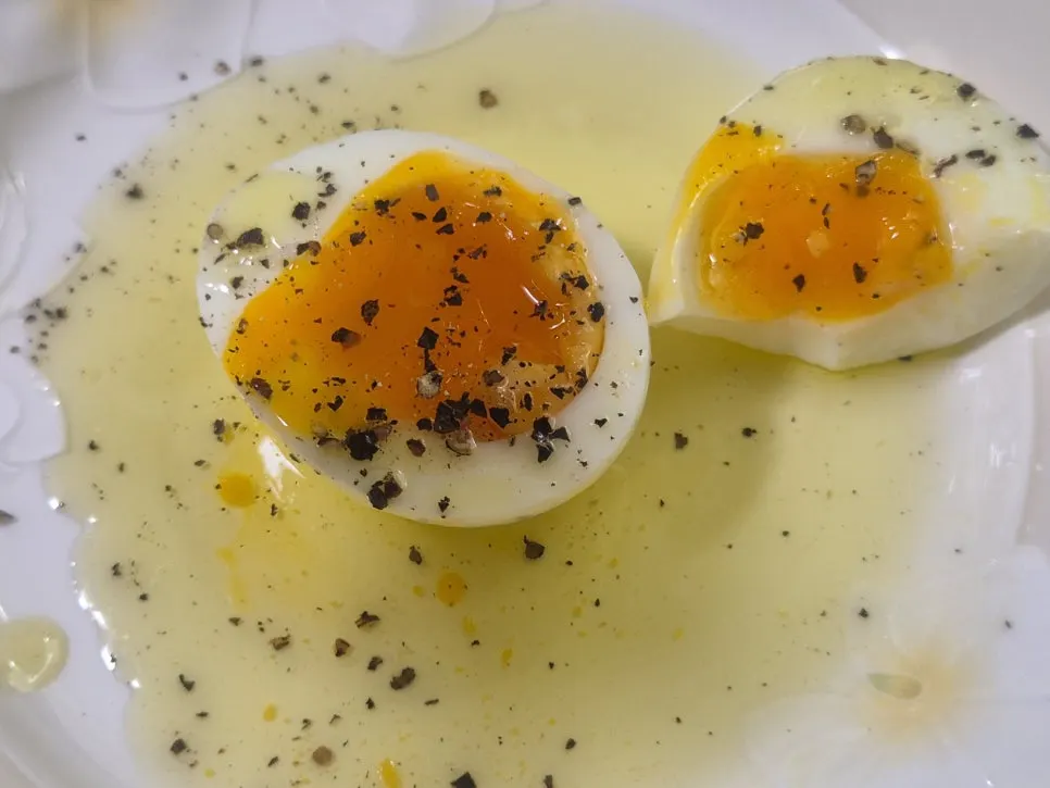 Soft-boiled egg topped with olive oil and pepper