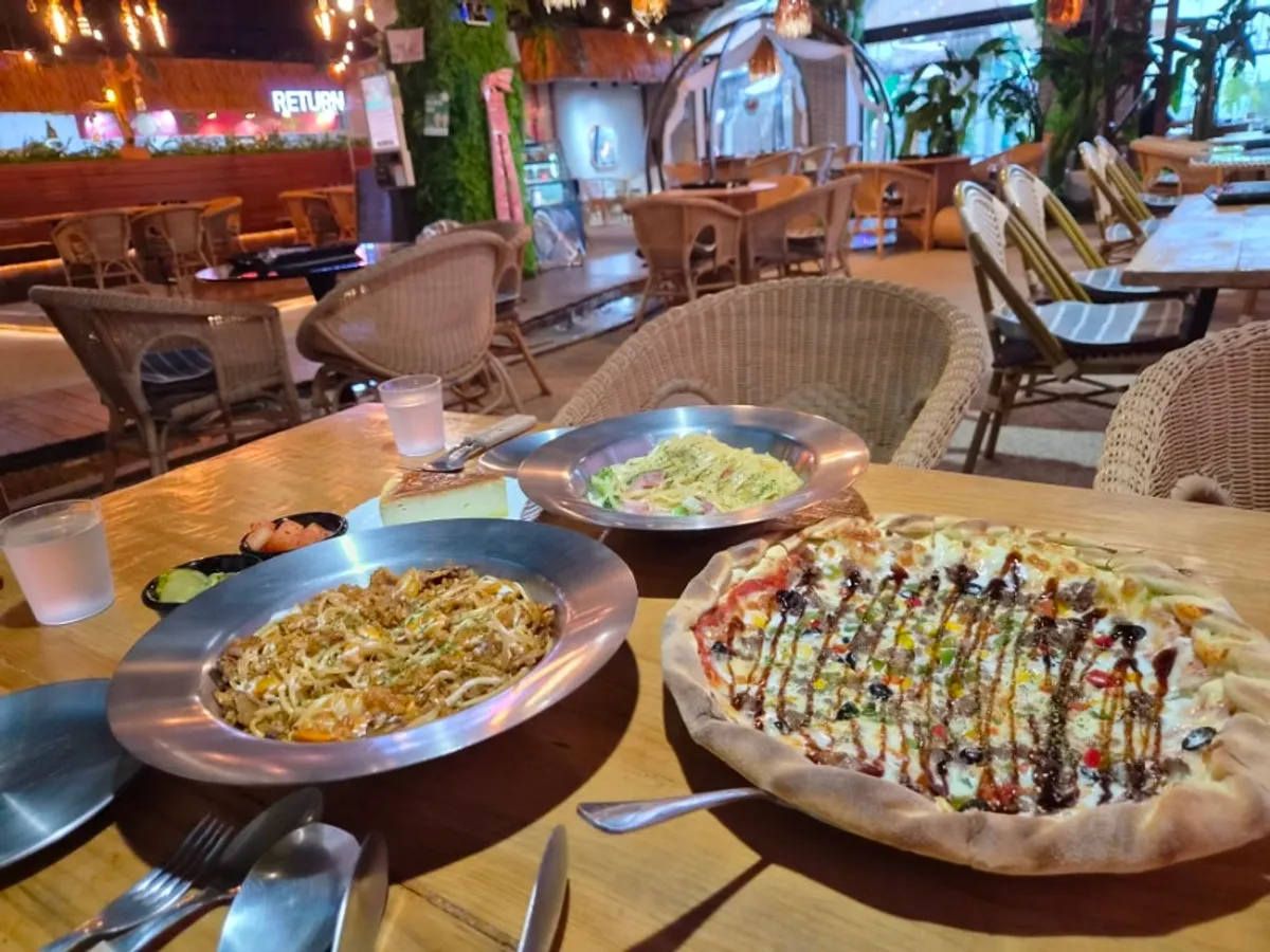 A full table of pizza, pasta, and pilaf
