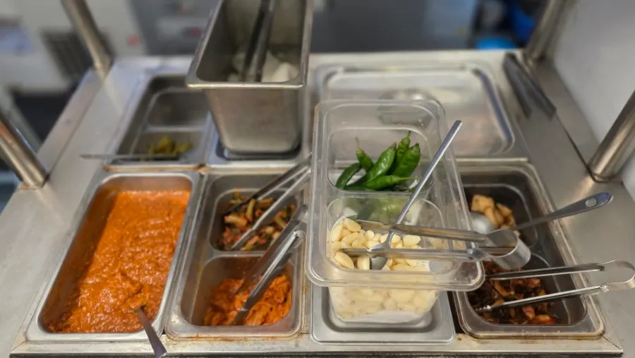 Side dishes and extra ingredients laid out at the self-serve bar