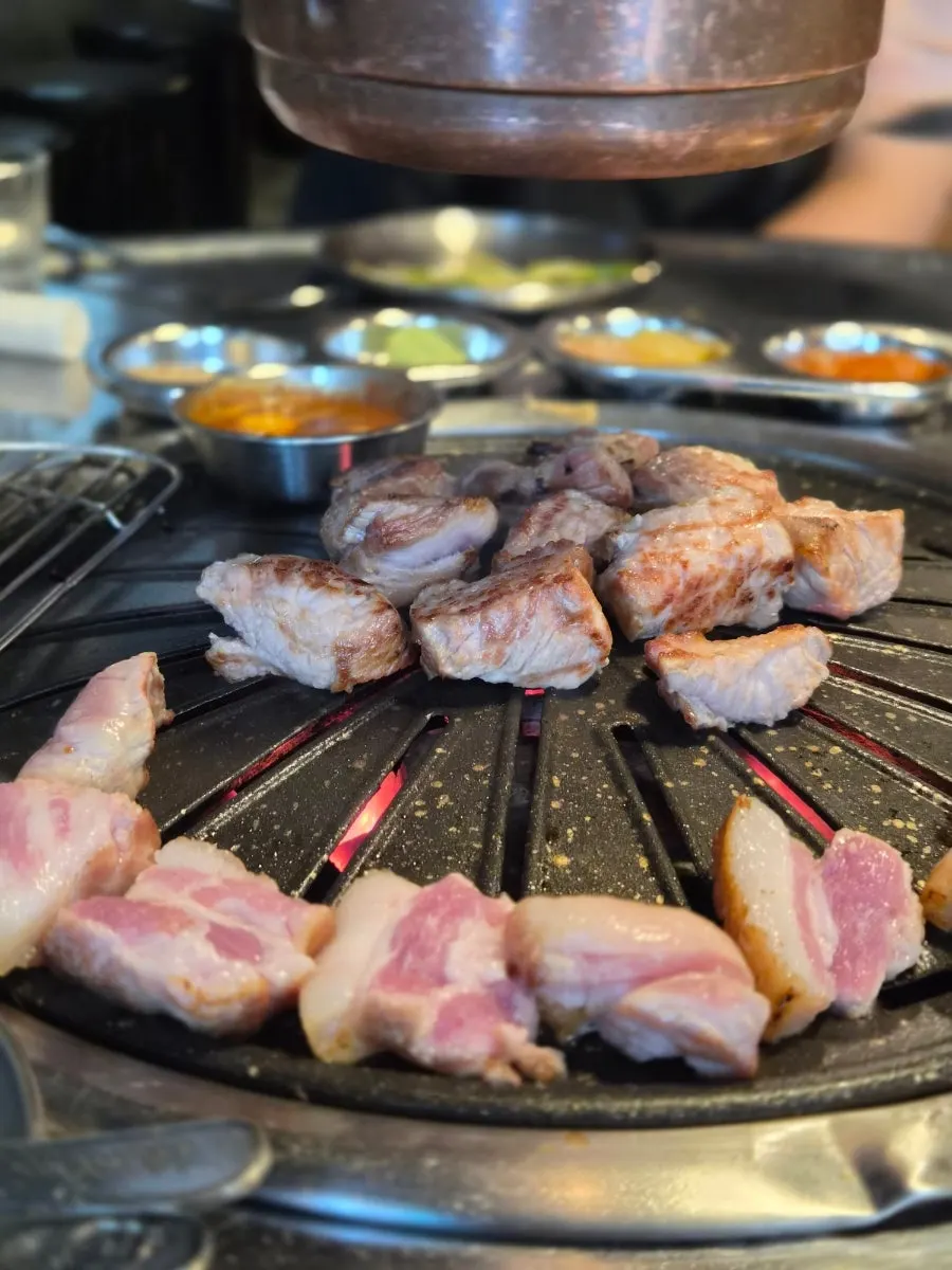 Staff member grilling thick pork neck on the grill