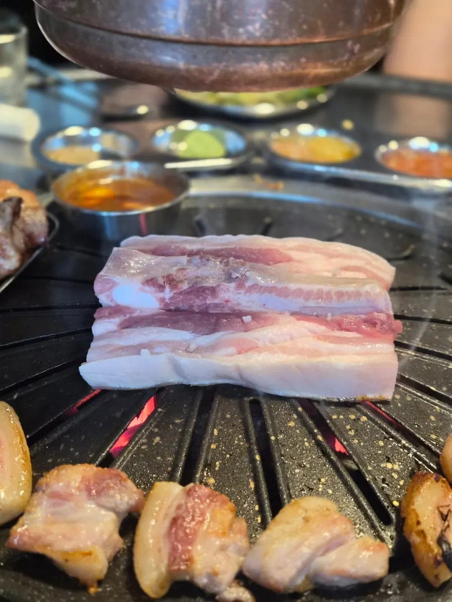 Pork neck cooking over charcoal