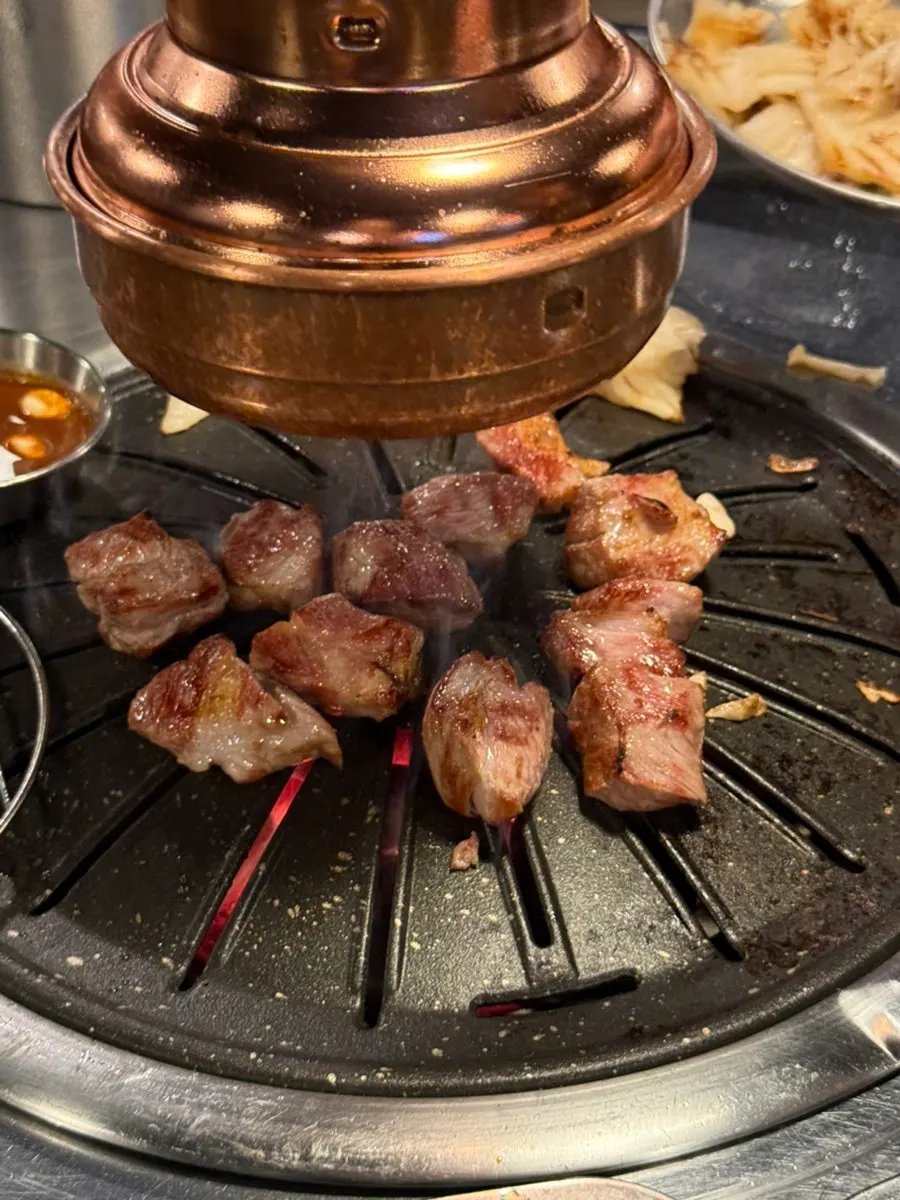 Meat grilling on the grill plate, with white kimchi seared in pork fat