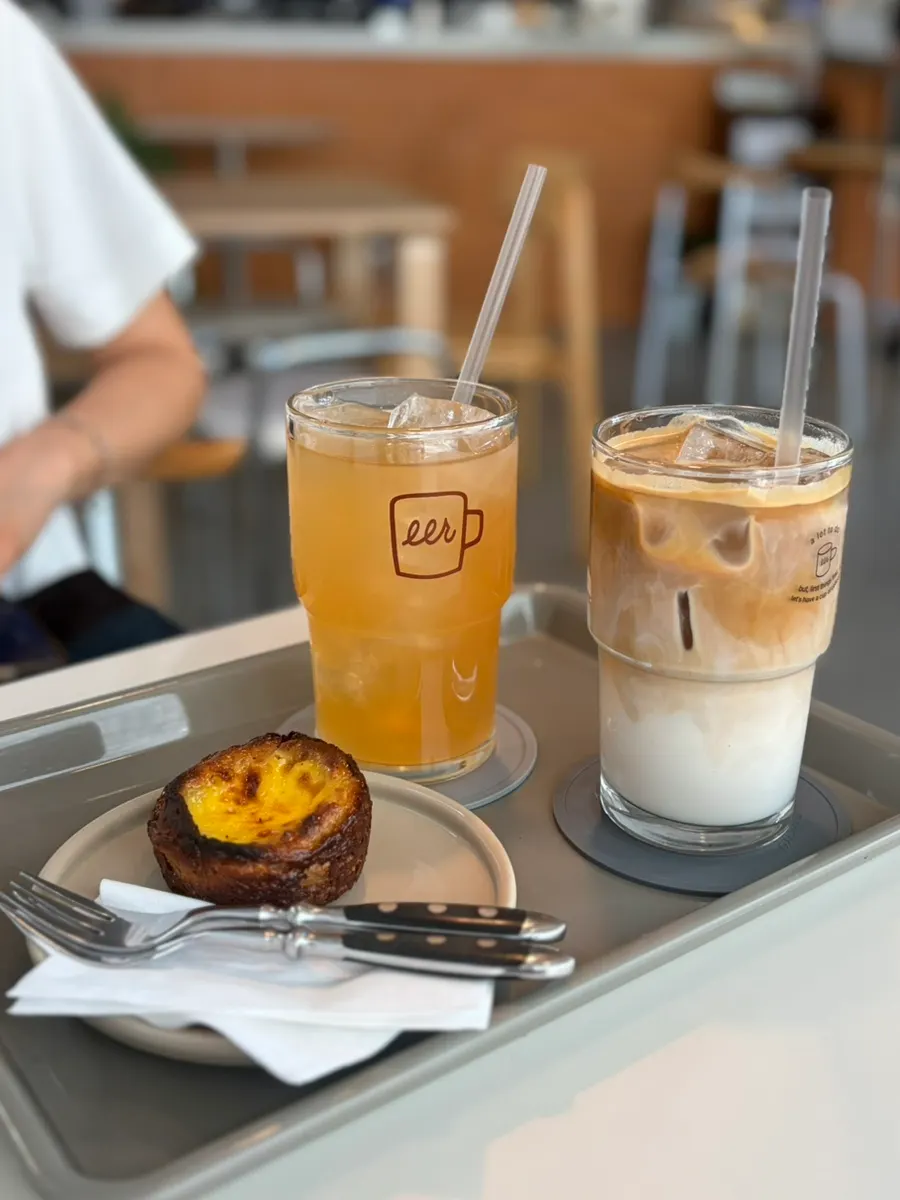 Two iced drinks and an egg financier set on the table