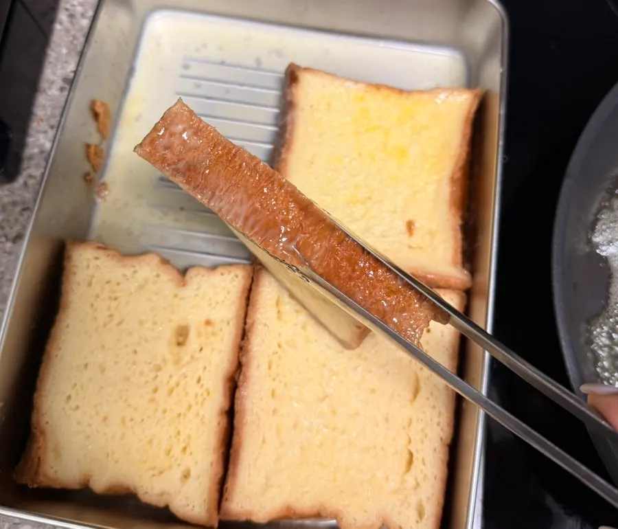 Milk bread French toast cooking in a pan