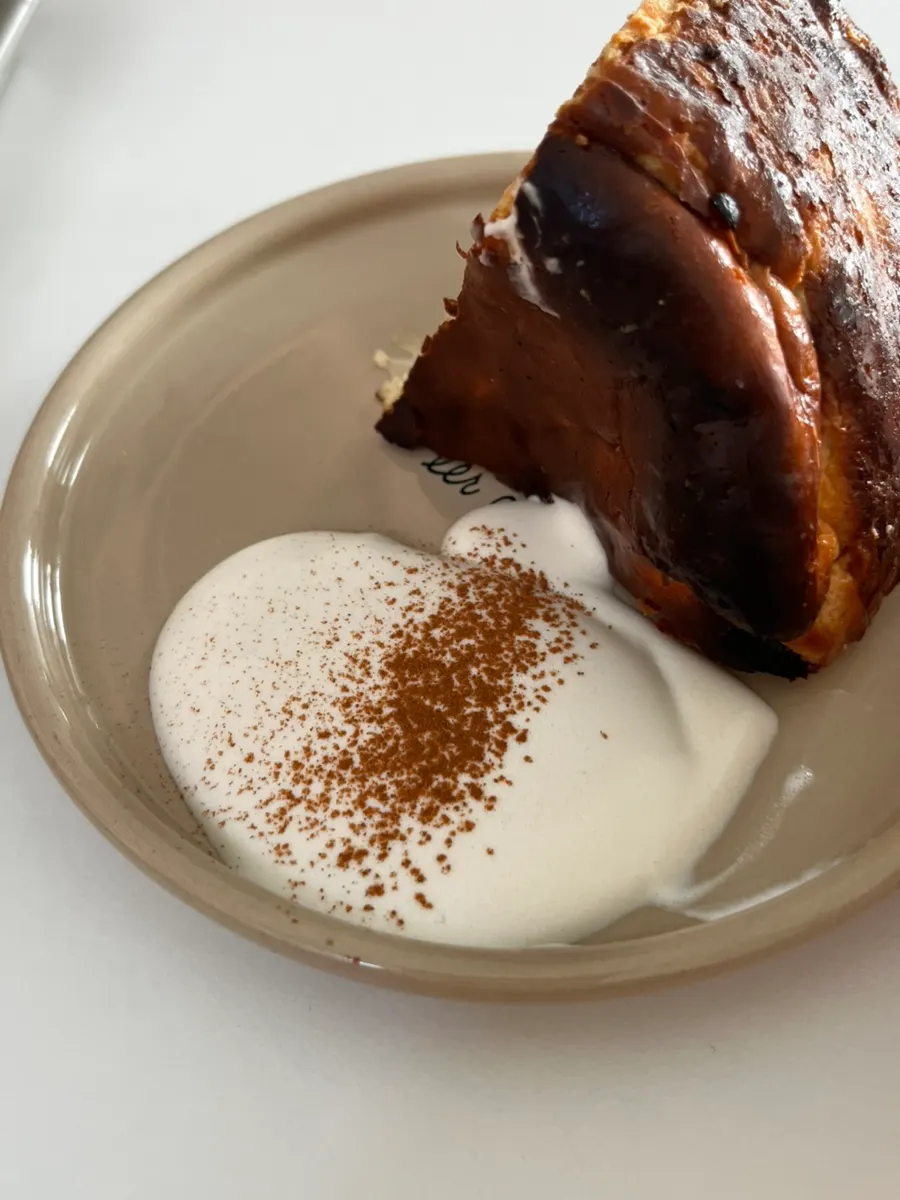 Cross-section of the chestnut Basque cheesecake served with cream