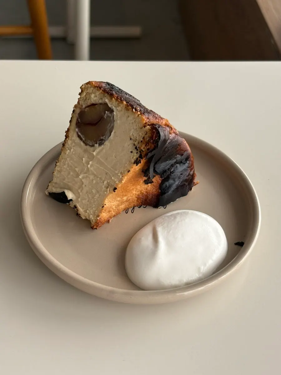 Cross-section of the chestnut Basque cheesecake with cream on the side
