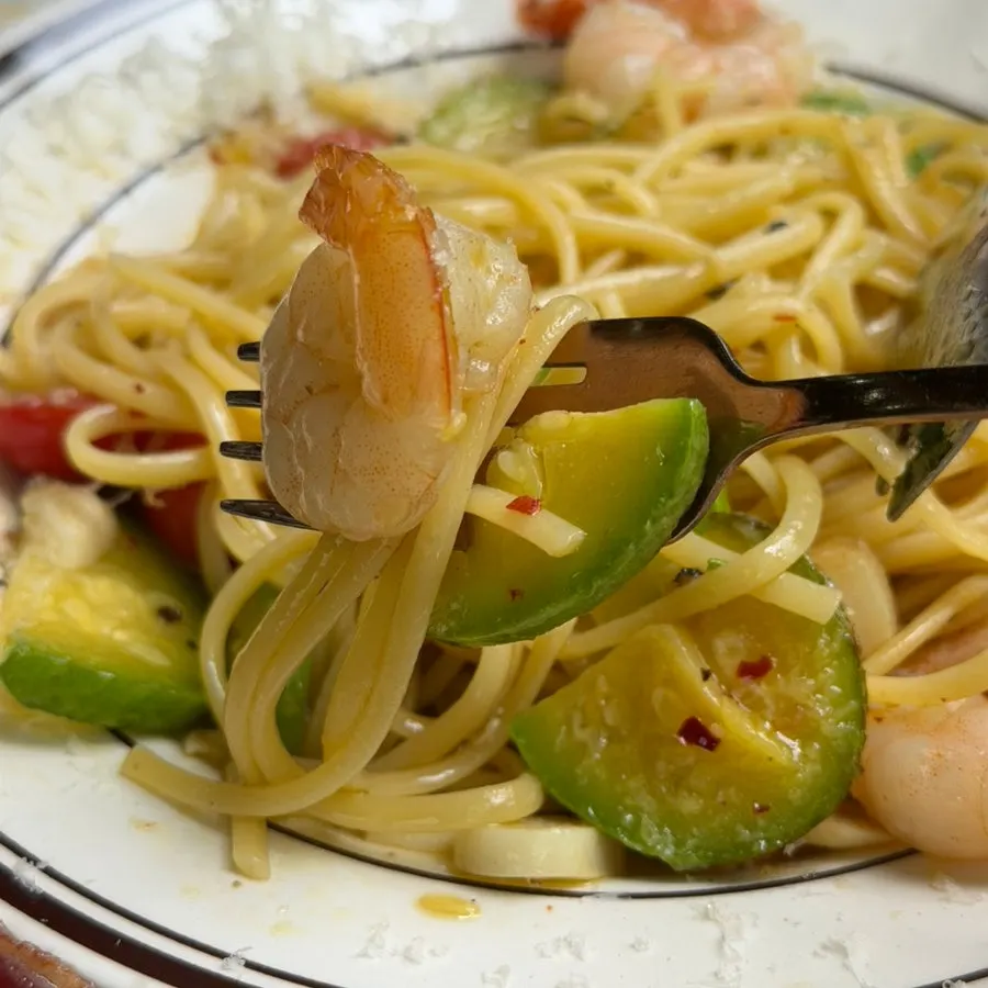 Oil pasta noodles and shrimp twirled on a fork