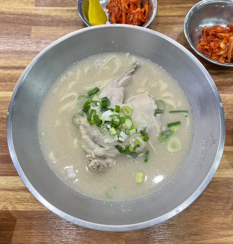 A bowl of dak kalguksu topped with half a chicken