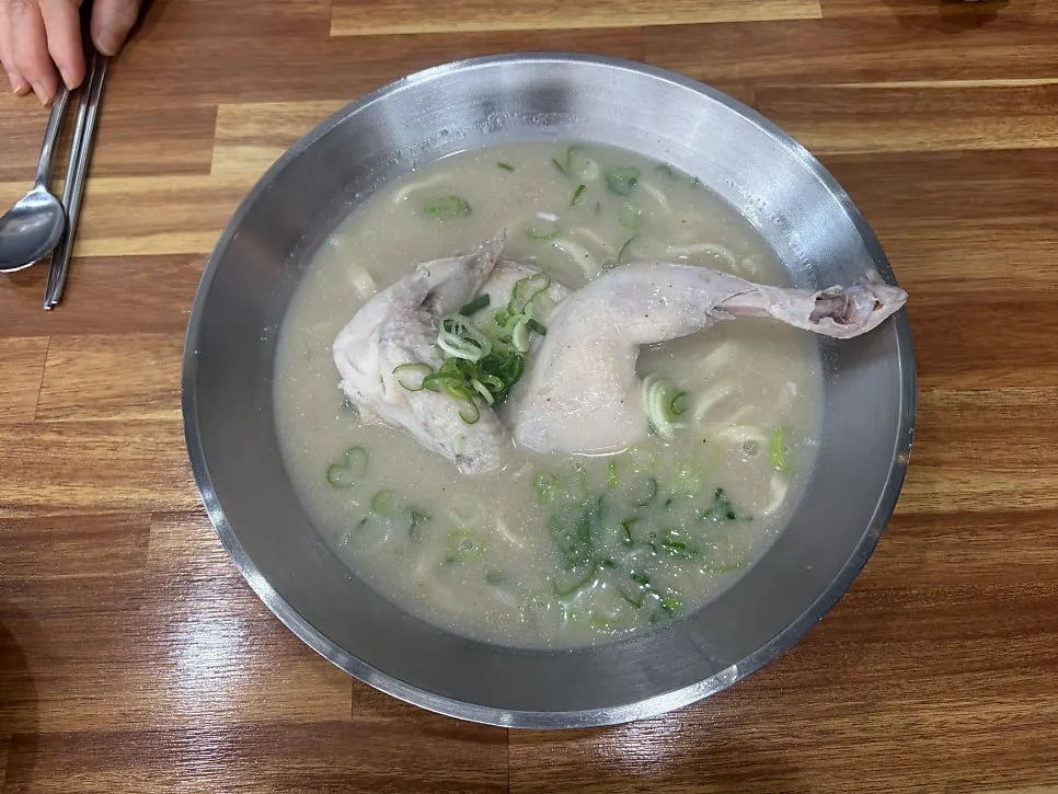 A bowl of chicken kalguksu topped with a whole half chicken
