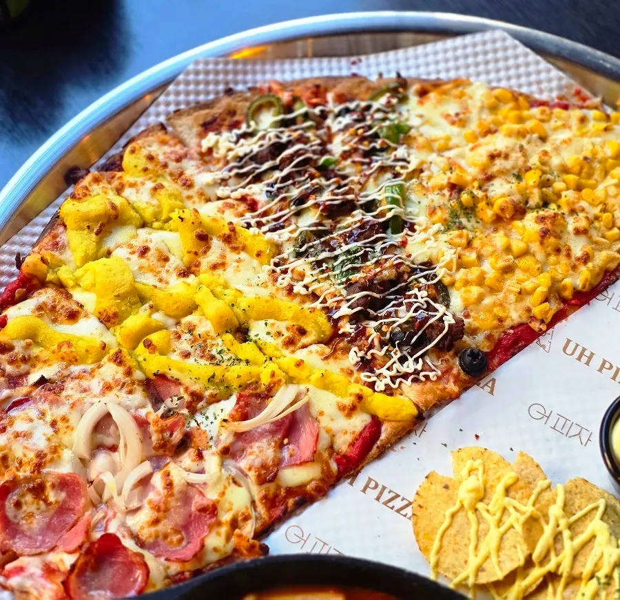 Mesa servida con la media pizza, el tteokbokki y la ensalada del Premium Set A
